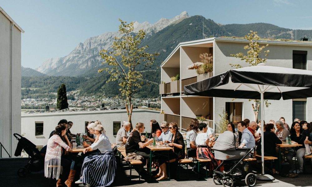 Gäste des ZIMA Sommerfest in Schwaz auf dem Vorplatz des ZIMA Projekts Minkuswiese auf Bierbänken